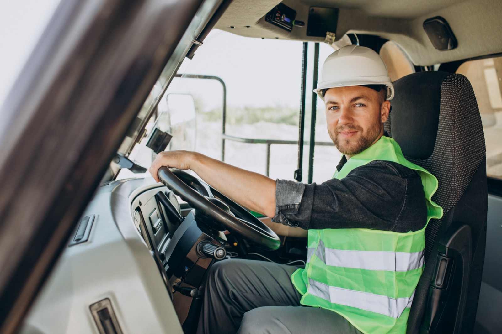 DR Transport driver at the wheel in a hi-vis vest and safety helmet